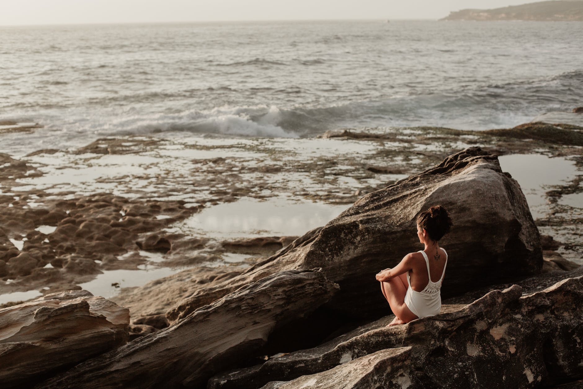 photo of woman sitting on rock