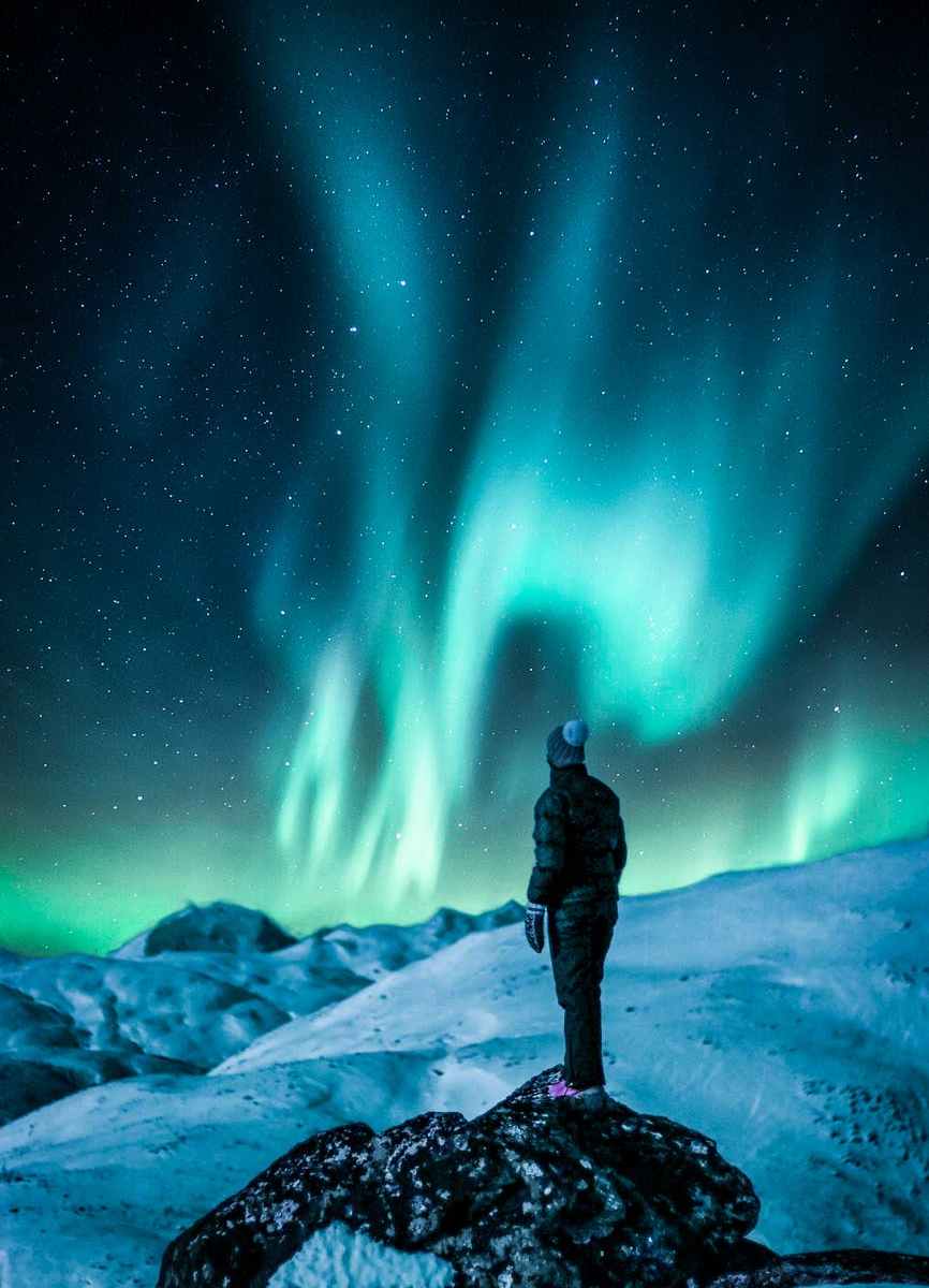 man standing on a rock near snow covered land